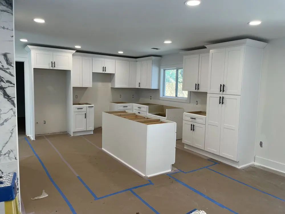 Modern kitchen under renovation with white cabinets.