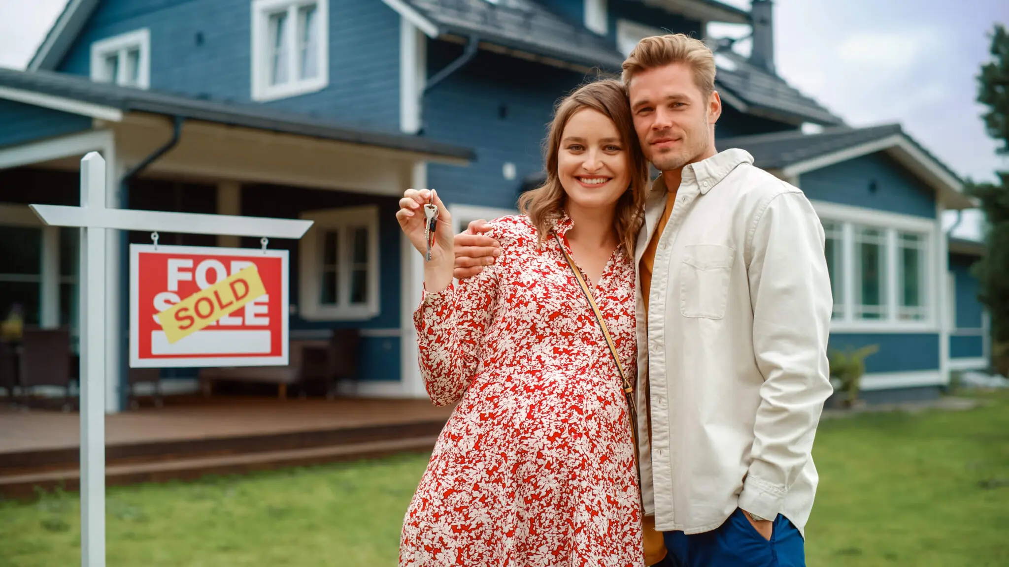 Couple smiling with keys outside new home.
