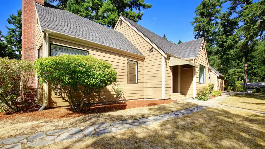 Brown house with sloped roof and garden.