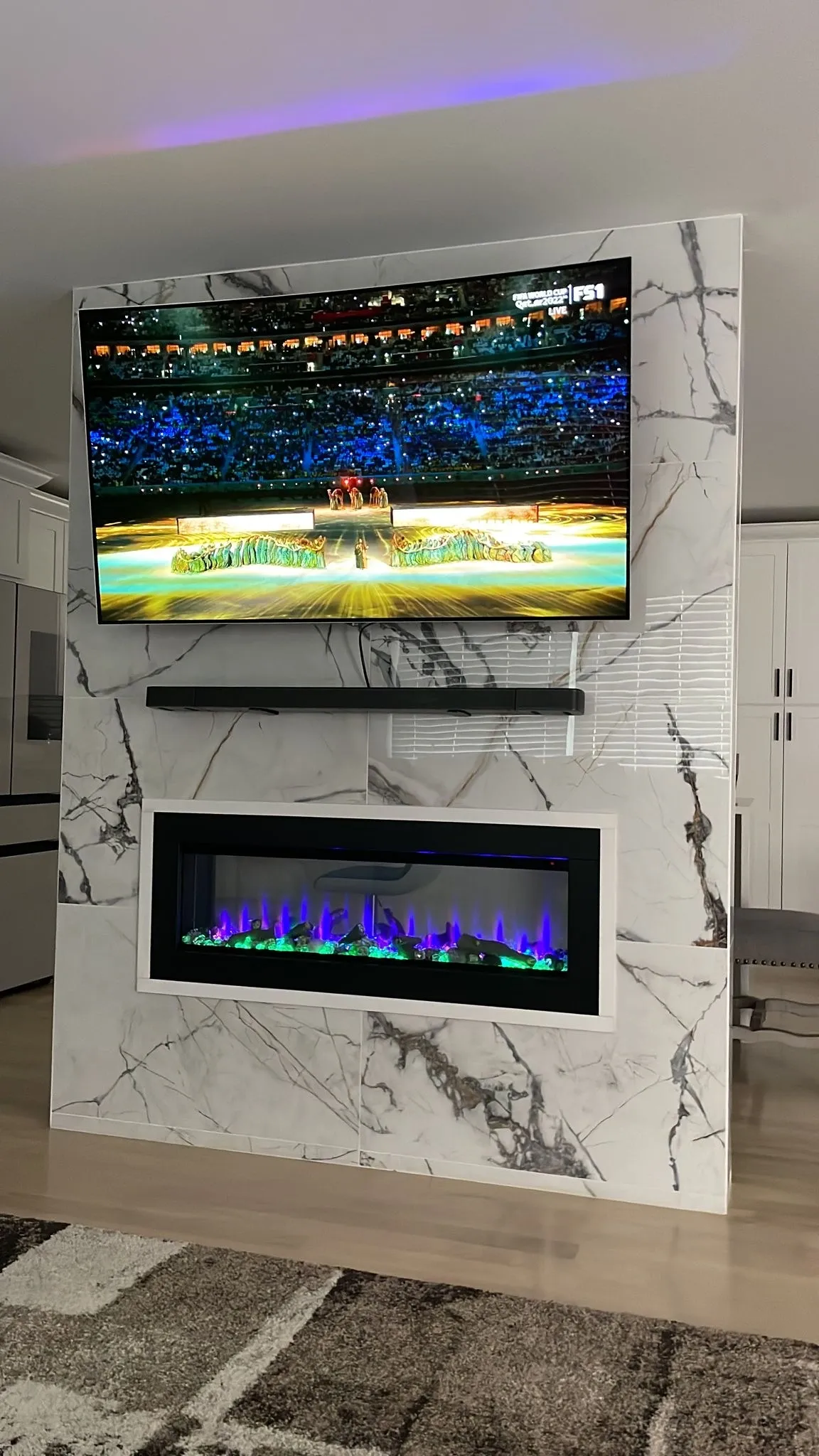 TV above modern fireplace in living room.